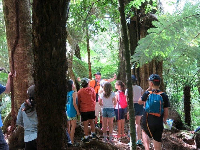 A park ranger talking to a group of children among the trees