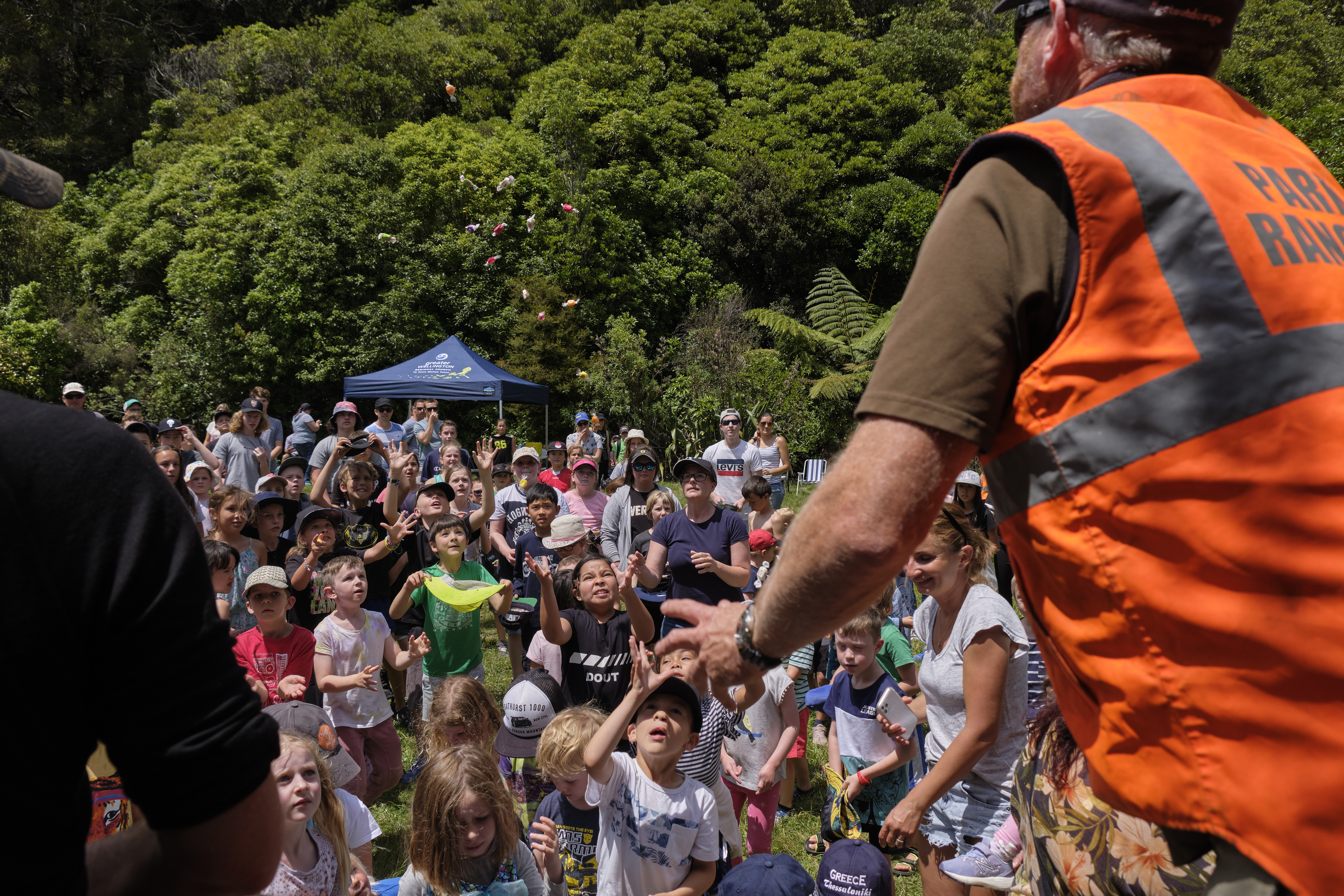 A park ranger tossing lollies into a crowd of children