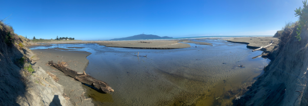 View of Waimeha Stream’s position on Waikanae Beach, seen from the dune near Field Way and facing west toward the sea, with Kāpiti Island visible on the horizon.