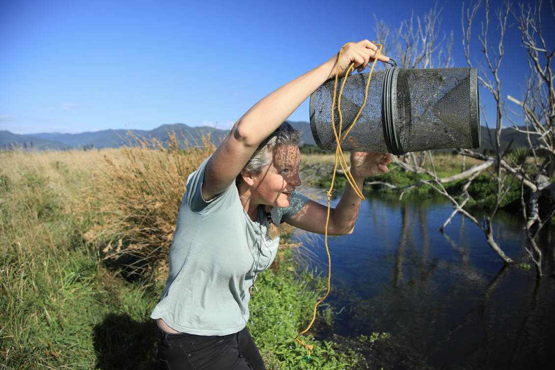 A woman holds up a trap to check it