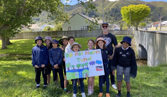 Students and a teacher from Naenae Primary School show off their "Do not harm tuna" sign